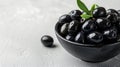 a black ceramic bowl with dark black olives