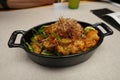 Black ceramic bowl filled with fried fish presented on a white tabletop Royalty Free Stock Photo