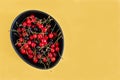 Black ceramic bowl with wild cherries on yellow background. Copy Space Royalty Free Stock Photo