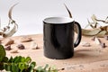 Black ceramic mug on wooden desktop next to scattered crystals, green twigs and small stones against white background Royalty Free Stock Photo