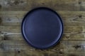 Black ceramic plate on dark brown wooden table background