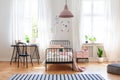 Black chair at desk next to bed in girl`s room interior with pink lamp above carpet Royalty Free Stock Photo