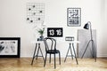 Black chair at white desk with desktop computer and plant in modern workspace interior. Real photo