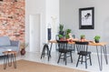 Black chairs at dining table and poster in flat interior with grey sofa against red brick wall Royalty Free Stock Photo