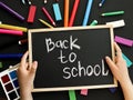 black chalk board with handwritten Back to school in children& x27;s hands and school felt-tip pens, paints, pen Royalty Free Stock Photo
