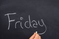 Woman`s hand writing the day of the week on a blackboard with white chalk, Friday Royalty Free Stock Photo