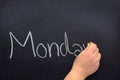 Woman`s hand writing the day of the week on a blackboard with white chalk, Monday Royalty Free Stock Photo