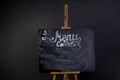 Black chalkboard with coffee menu and streaks erased chalk. Stands on a wooden easel, isolated on a dark background