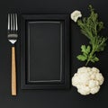 Black chalkboard frame with fresh cauliflower and herbs on dark background Royalty Free Stock Photo