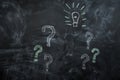 Drawn on black chalkboard question marks and light bulb Royalty Free Stock Photo