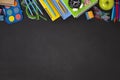 Black chalkboard school background with school supplies and stationery items, empty copy space for text Royalty Free Stock Photo