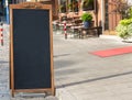 Black chalkboard stand on wood for a restaurant menu in the street Royalty Free Stock Photo