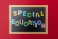 Black chalkboard with wooden frame, text special education in colorful letters, red wall background Royalty Free Stock Photo