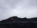 Black charcoal mountain silhouette against the cloudy sky