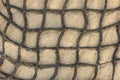 Black checkered rope net on light sand close up. natural surface texture Royalty Free Stock Photo