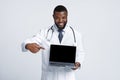 Black cheerful doc pointing at blank laptop screen