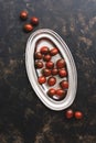 Black cherry tomato in a metal dish on a dark rustic background. Top view, flat lay Royalty Free Stock Photo