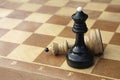 Two chess kings on wooden chess board. White figure lying defeated next to black winner Royalty Free Stock Photo