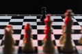 Black chess pawn against an army of white chess pieces on a chessboard on a black background Royalty Free Stock Photo