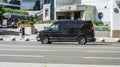 Black Chevrolet Express with left-side passenger doors driving on the street. Luxury van Chevrolet Express in motion on city road