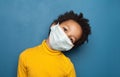 Black child in medical protective face mask on blue background