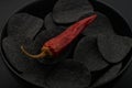 Black chips and red hot peppers on black background Royalty Free Stock Photo