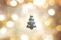 Black christma tree outline on gold, yellow, white, black, and grey color bokeh background.