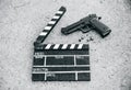 Black clapperboard with gun on background. Directing and filming cinema movie. Detective criminal story