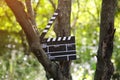 Black clapperboard hanging on the tree in park . Directing and filming of some amateur cinema movie