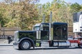 Black classic big rig semi truck tractor with extended cab for truck driver rest transporting cargo in refrigerated semi trailer Royalty Free Stock Photo
