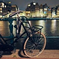 Black bike by the canal at night in Amsterdam Royalty Free Stock Photo