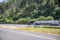 Black classic shiny big  rig semi truck transporting liquid cargo in stainless steel tank semi trailer running on the highway road Royalty Free Stock Photo