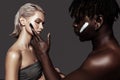 African-American man putting some black clay mask on woman