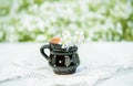 Black clay mug, sunny summer, wildflowers in a vase on a lace knitted tablecloth, lace. A village and vintage, a gentle cozy