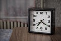 Black clock alarm on a bedside table on a bed and window background Royalty Free Stock Photo