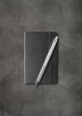 Black closed notebook with a pen on dark concrete background Royalty Free Stock Photo