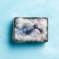 Black coal bar of soap in foam on blue background Royalty Free Stock Photo