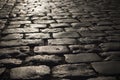 Black cobbled stone road background with reflection of light seen on the road. Black or dark grey stone pavement texture.