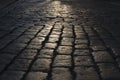 Black cobbled stone road background with reflection of light seen on the road. Black or dark grey stone pavement texture.