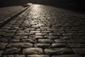 Black cobbled stone road background with reflection of light seen on the road. Black or dark grey stone pavement texture.