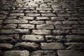 Black cobbled stone road background with reflection of light seen on the road. Black or dark grey stone pavement texture.