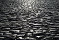 Black cobbled stone road background with reflection of light seen on the road Royalty Free Stock Photo