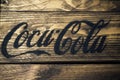 Black Coca Cola logo on rustic weathered wood