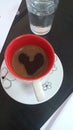 Black coffe cup with heart shape and glass of water  on a work desk Royalty Free Stock Photo