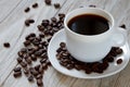 Black coffe and roasted beans in a white mug on wooden surface Royalty Free Stock Photo