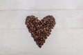 Black coffee beans. In the form of a heart. On a white wooden background. Minimalism. For the design and writing of text Royalty Free Stock Photo