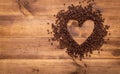 Black coffee beans seed in heart shape on brown wooden table, dark cofee arabica robusta roasted grain flavor aroma cafe, natural Royalty Free Stock Photo