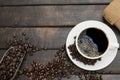 black coffee with beautiful froth in a classic coffee cup with roasted coffee beans hemp sack and a scoop on wooden table Royalty Free Stock Photo