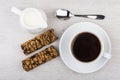 Black coffee, cereal bars and jug of milk on table