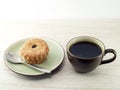 black coffee in dark brown ceramic cup and brown cup cake with silver metal teaspoon on pottery saucer on wooden table top Royalty Free Stock Photo